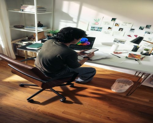 A professional reviewing screen brightness and seating posture at a well-lit home office desk