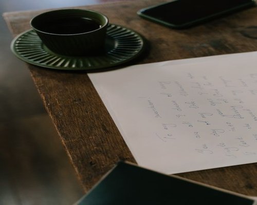A cup of breakfast tea sitting on a wooden table next to paper notes